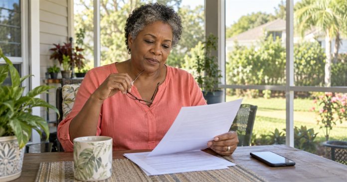 Woman holding reading glasses while reviewing a paper agreement on her screened home porch