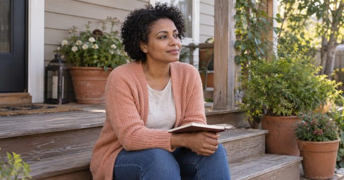 Woman with a notebook sitting thoughtfully on the steps of a home garden porch