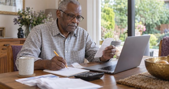 Checking reading receipts at home A man comparing a printed receipt with notes and a laptop at his home table.