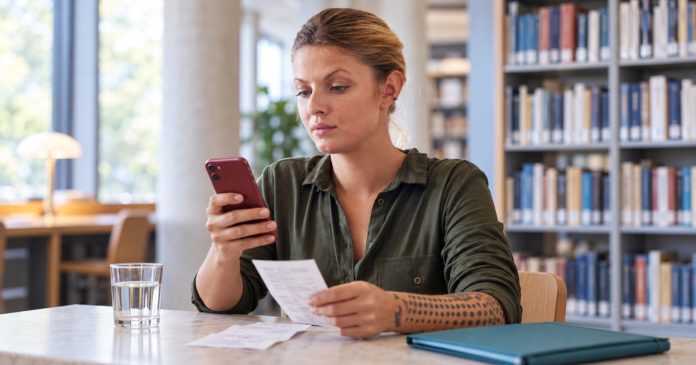 Woman reviewing phone messages and payment records before sending more money.